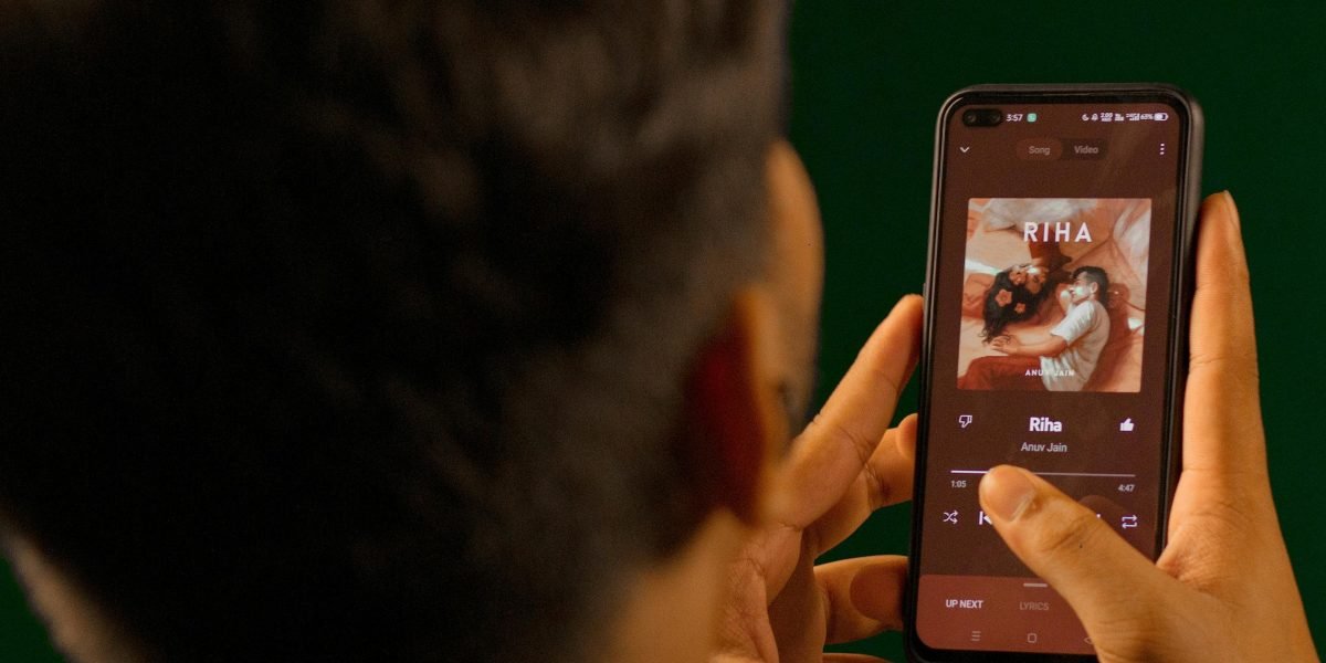 A person thoughtfully selecting calming music on their device, preparing for their bedtime routine.