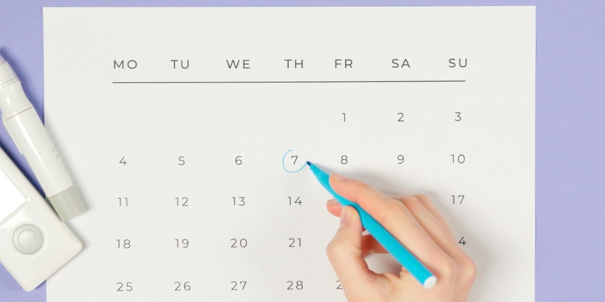 A person making a checkmark on a calendar, symbolizing the positive reinforcement of a new, healthy habit.