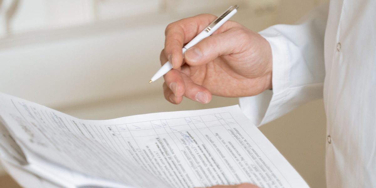 An individual carefully reviewing health information, possibly blood pressure readings or medical documents, to understand personal health trends.