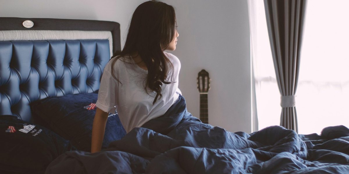 A person arranging their bedroom to create a peaceful and conducive environment for sleep and relaxation.