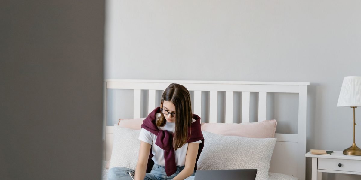 Someone setting up their bedroom environment, perhaps adjusting a speaker, as part of a calming bedtime routine.